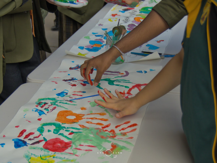 Students making hand prints with paint on paper