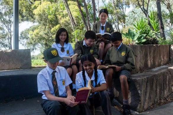 students reading books as they sit together outside