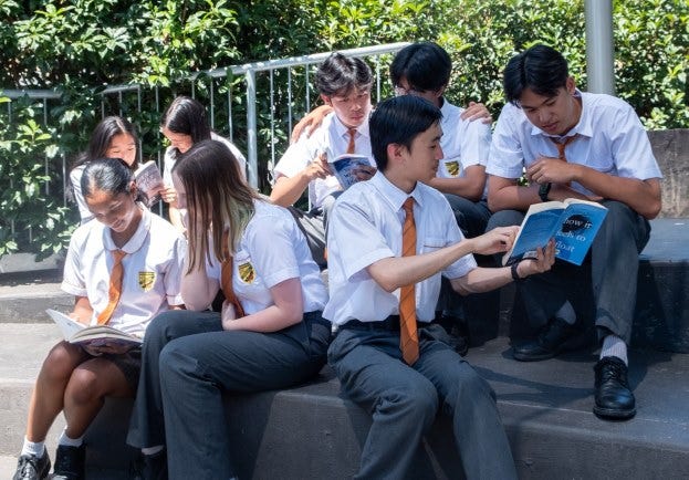students looking at books as they sit outside